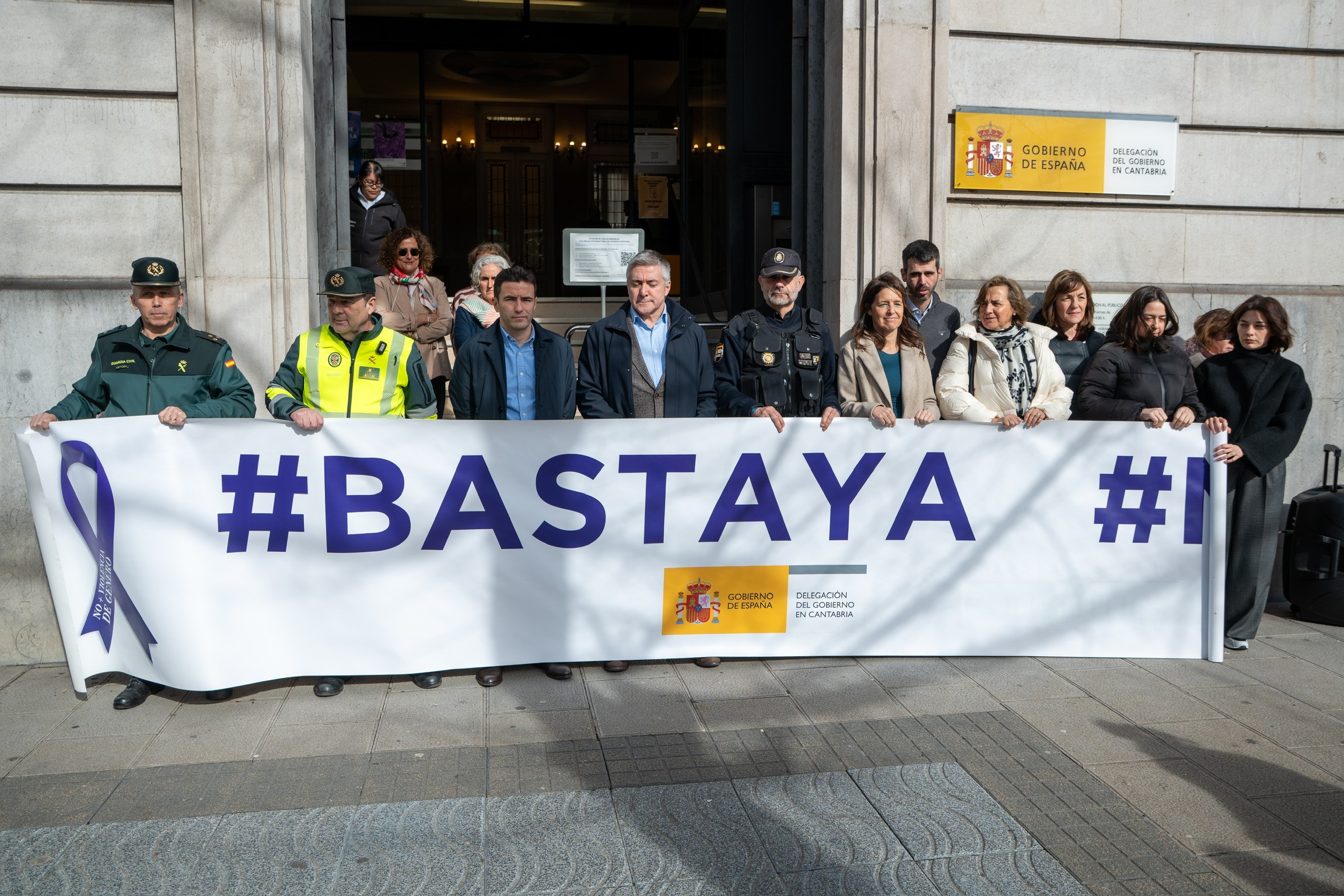 El delegado junto a otras autoridades manteniendo la pancarta Basta Ya