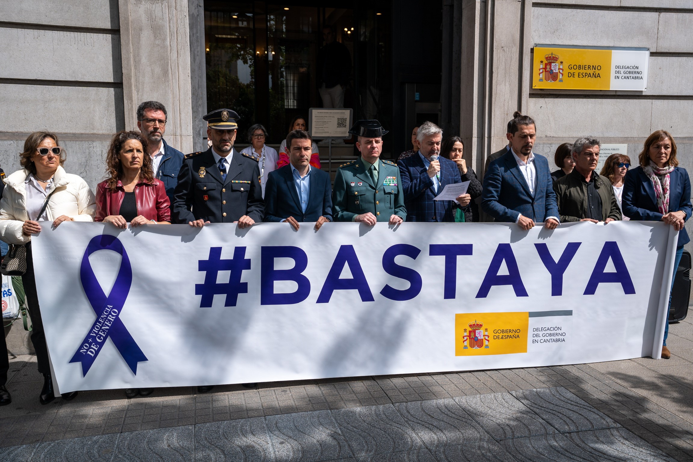 Personal de la Delegación y de las Fuerzas y Cuerpos de Seguridad del Estado tras la pancarta #BastaYa