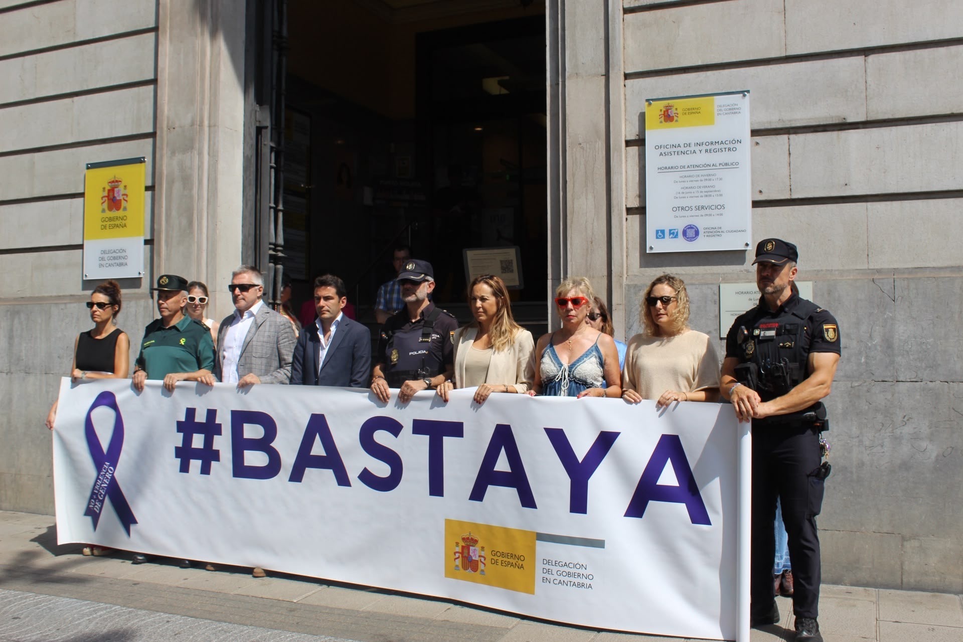 El delegado del Gobierno junto a otras autoridades en la puerta de la Delegación sosteniendo la pancarta #Basta Ya , durante el minuto de silencio