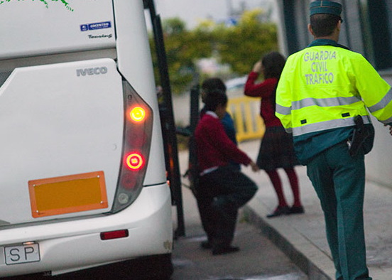 Niños subiendo a un autobús escolar bajo la vigilancia de un agente de tráfico