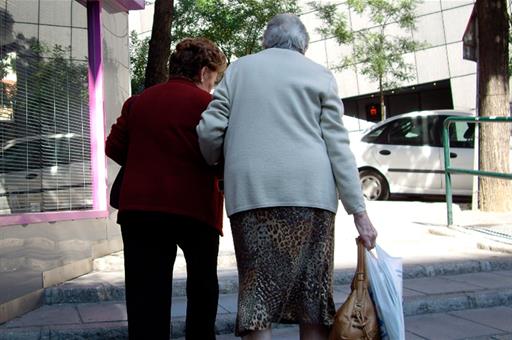 Dos mujeres de avanzada edad caminando agarradas del brazo por la calle