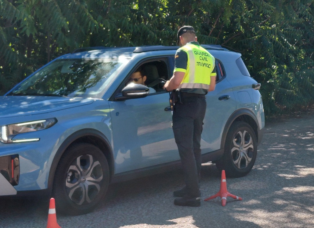 Un agente de Tráfico pidiendo documentación a un conductor con el vehículo detenido