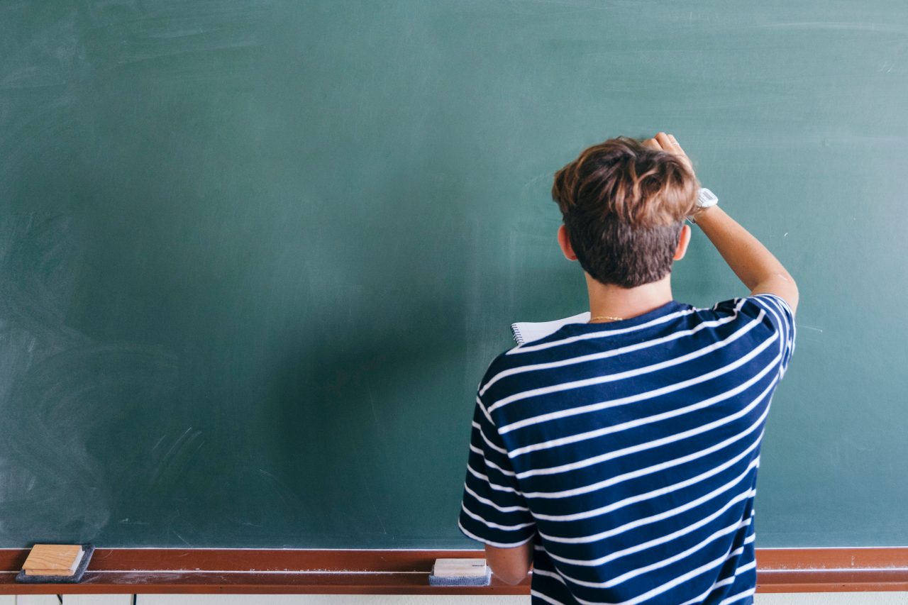 Persona de espaldas escribiendo en una pizarra
