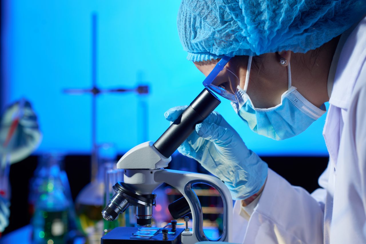 Persona trabajando con un microscopio en un laboratorio